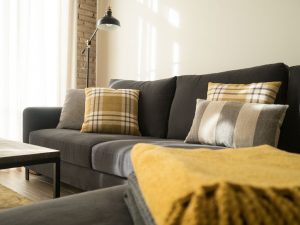 sofá gris con cojnes de diseño tonos tierra