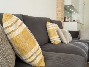 sofá tapizado gris con cojines de decoración